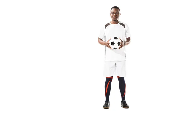 Volle Länge Ansicht der glücklichen jungen afrikanisch-amerikanischen Fußballspieler hält Ball und lächelt in die Kamera isoliert auf weiß — Stockfoto
