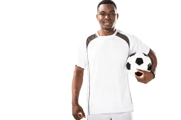 Joven afroamericano futbolista sosteniendo pelota y sonriendo a cámara aislada en blanco - foto de stock