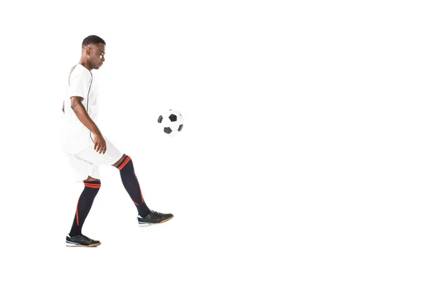 Side view of handsome young african american sportsman playing with soccer ball isolated on white — Stock Photo