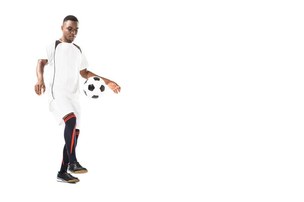 Vista completa de apuesto joven afroamericano deportista jugando con pelota de fútbol aislado en blanco - foto de stock