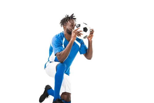 Sportsman afroamericano inginocchiato e tenendo il pallone da calcio isolato su bianco — Foto stock