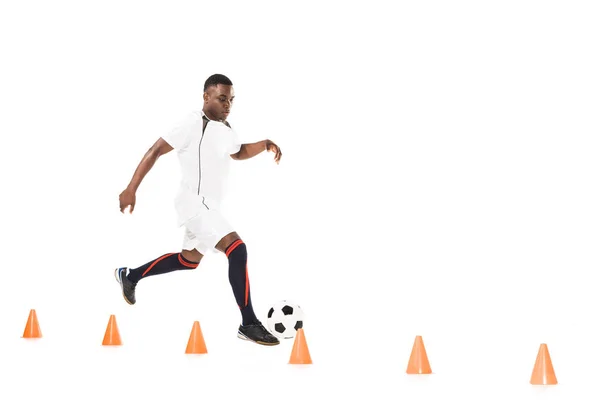 Junger afrikanisch-amerikanischer Sportler läuft und trainiert mit Fußball und Markierungskegeln isoliert auf weißem Grund — Stockfoto