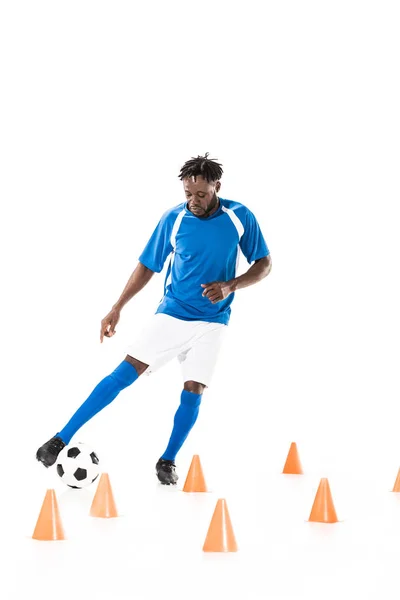 Vista completa del joven jugador de fútbol afroamericano entrenando con conos de pelota y marcador aislados en blanco - foto de stock