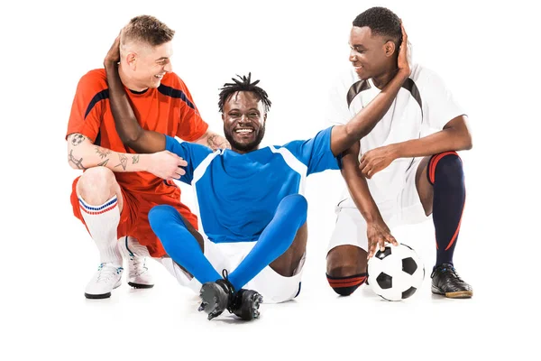 Feliz joven futbolistas multiétnicos con pelota aislada en blanco - foto de stock
