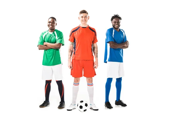 Confiados jóvenes jugadores multiétnicos de fútbol de pie juntos y sonriendo a la cámara aislada en blanco - foto de stock