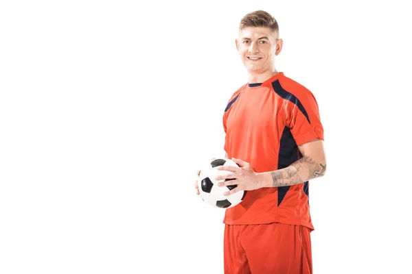 Glücklicher junger athletischer Mann in Sportbekleidung mit Fußballball in der Hand und lächelnd in die Kamera isoliert auf weiß — Stockfoto