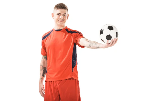 Feliz joven deportista sosteniendo pelota de fútbol y sonriendo a la cámara aislado en blanco - foto de stock