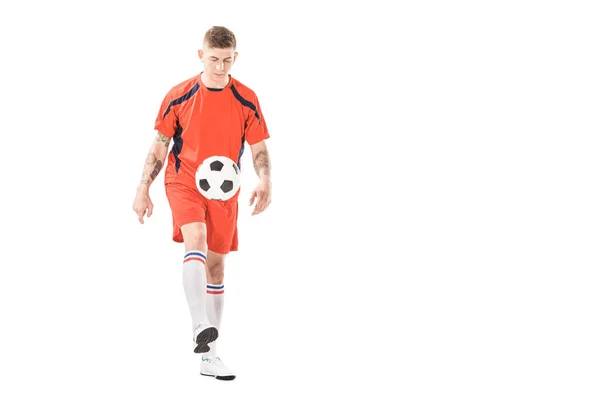 Спортивний молодий спортсмен у спортивному одязі грає з футбольним м'ячем ізольовано на білому — стокове фото