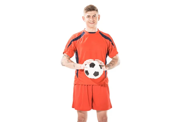 Beau jeune footballeur tenant le ballon et souriant à la caméra isolé sur blanc — Photo de stock