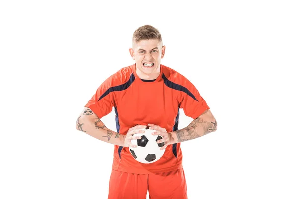 Arrabbiato giovane giocatore di calcio tenendo palla e guardando la fotocamera isolata su bianco — Foto stock