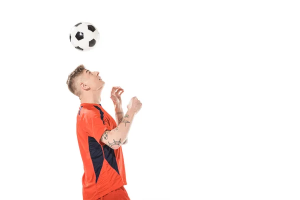 Junger Fußballer schlägt Ball mit dem Kopf und blickt isoliert auf weiß — Stockfoto