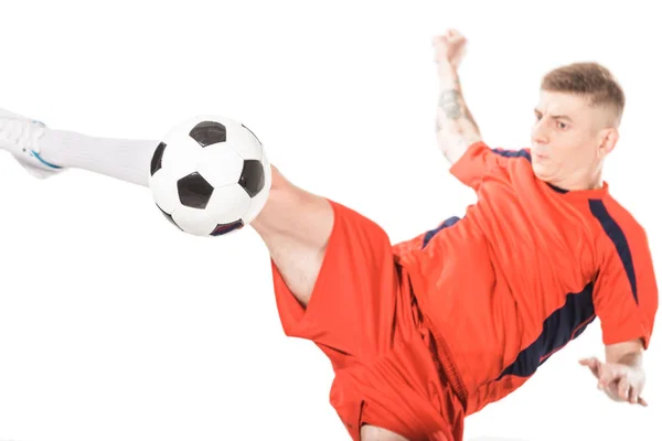 Vista ravvicinata del giovane giocatore di calcio che colpisce palla con gamba isolata sul bianco — Stock Photo