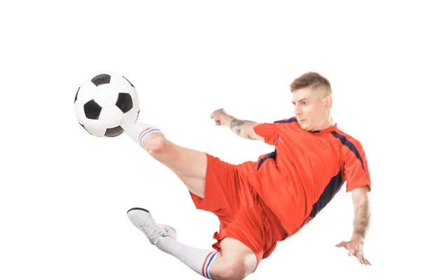 Jovem jogador de futebol chutando bola no salto isolado no branco — Fotografia de Stock