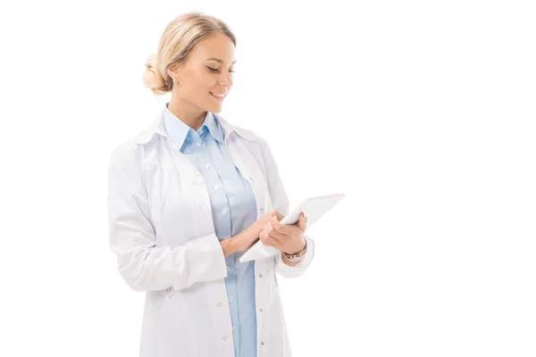 Щаслива молода жінка-лікар, що працює з планшетом ізольовано на білому — стокове фото