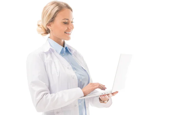 Sorridente jovem médico trabalhando com laptop isolado em branco — Fotografia de Stock