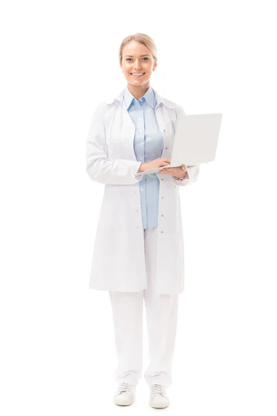 Sorridente jovem médica com laptop olhando para a câmera isolada no branco — Fotografia de Stock