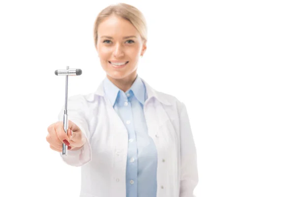 Lächelnde junge Neurologin hält Reflexhammer in der Hand und blickt isoliert auf weiße Kamera — Stockfoto