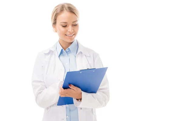 Sonriente joven doctora escribiendo en portapapeles aislado en blanco - foto de stock