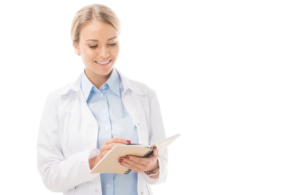 Счастливая молодая женщина врач записи в блокноте изолированы на белом — стоковое фото