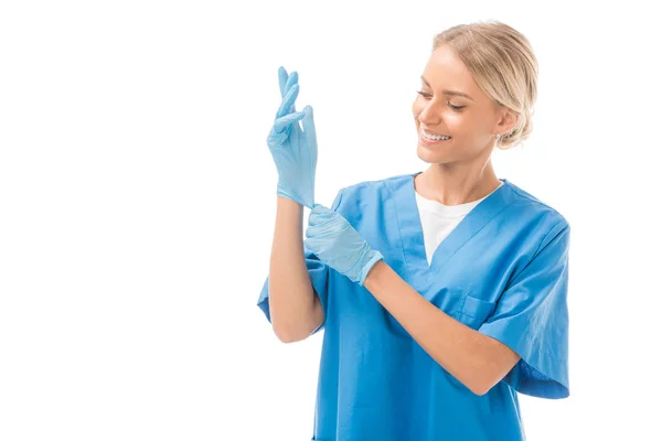 Beautiful young nurse putting on rubber gloves isolated on white — Stock Photo