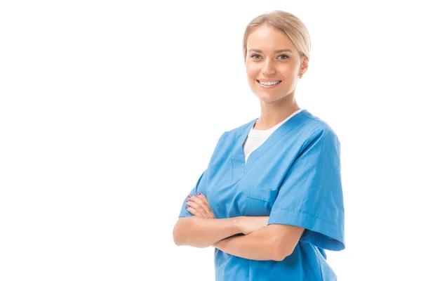 Heureuse jeune infirmière avec les bras croisés regardant caméra isolée sur blanc — Photo de stock
