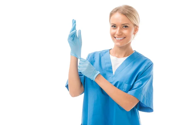 Glücklich junge Krankenschwester zieht Gummihandschuhe isoliert auf weiß — Stockfoto