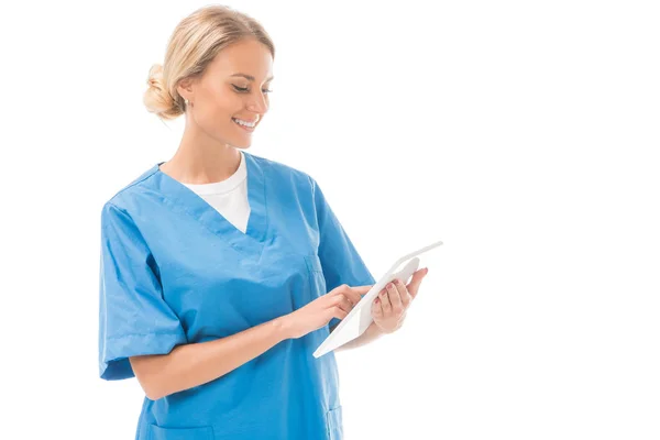 Усміхнена молода медсестра працює з цифровим планшетом ізольовано на білому — стокове фото