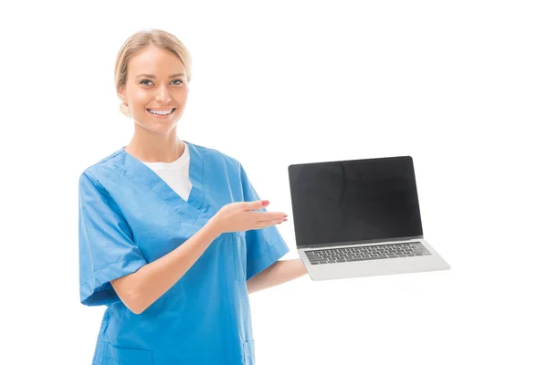 Happy young nurse pointing at laptop isolated on white — Stock Photo