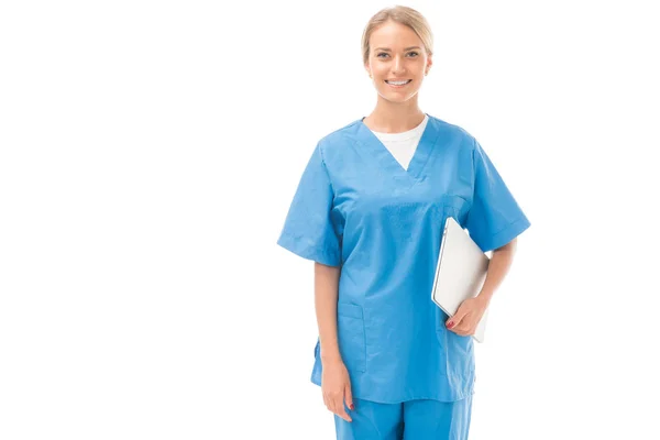 Enfermera joven sonriente con portátil mirando a la cámara aislada en blanco - foto de stock