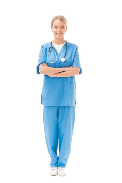 Молодая медсестра со скрещенными руками смотрит на камеру, изолированную на белом — стоковое фото
