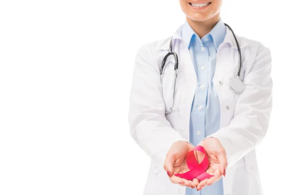 Recortado disparo de sonriente joven médico que sostiene ayudas conciencia cinta roja símbolo aislado en blanco - foto de stock