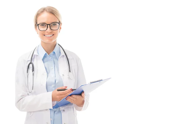 Selbstbewusste junge Ärztin mit Klemmbrett blickt isoliert auf weiße Kamera — Stockfoto