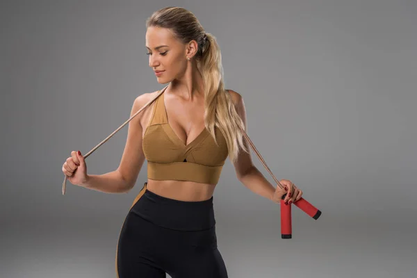 Jeune femme sportive avec corde à sauter sur gris — Photo de stock