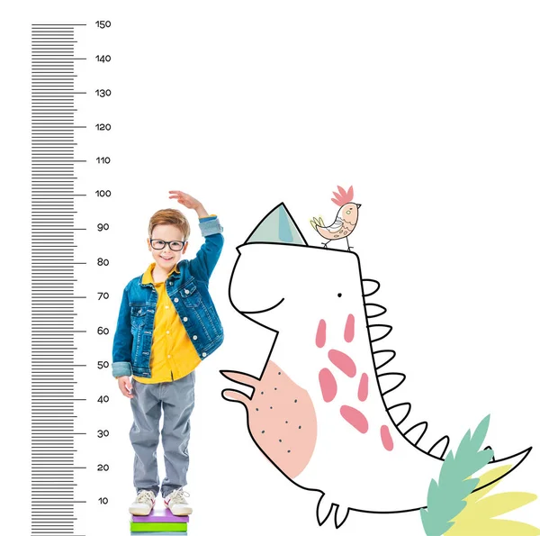 Junge, der auf Bücherstapel steht, um höher zu sein, isoliert auf weiß mit imaginären Dinosaurier- und Wachstumsmaßen — Stockfoto