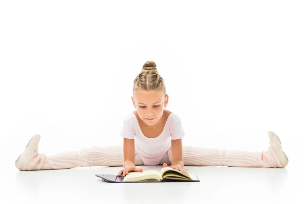 Pequeña bailarina concentrada leyendo libro y haciendo cordel aislado sobre fondo blanco - foto de stock