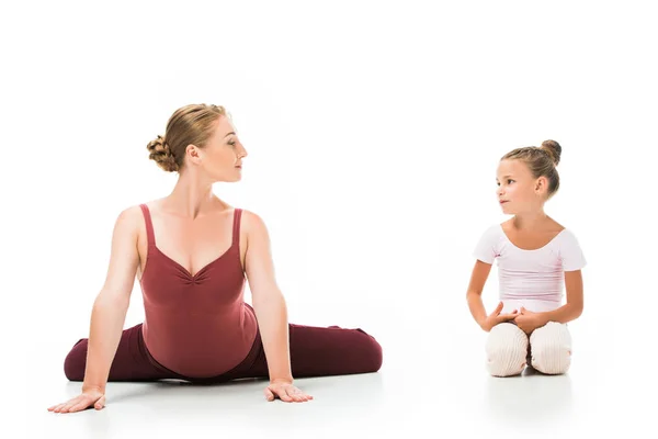 Sorridente adulto femmina allenatore mostrando esercizio alla piccola ballerina isolata su sfondo bianco — Foto stock
