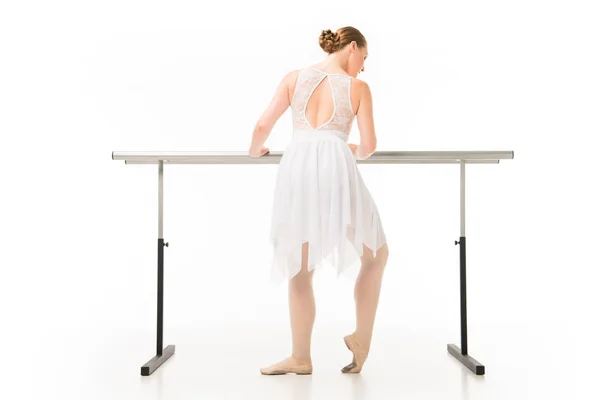 Vista trasera de la bailarina adulta en tutú ejercitándose en el soporte de la barra de ballet aislado sobre fondo blanco - foto de stock