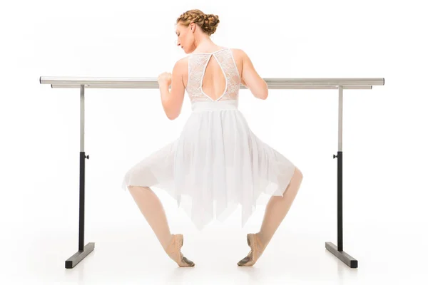 Vue arrière d'une jolie ballerine en tutu faisant de l'exercice sur un support de barre de ballet isolé sur fond blanc — Photo de stock