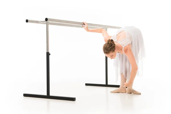 Bailarina em tutu e sapatos pointe praticando no ballet barre stand isolado no fundo branco — Fotografia de Stock