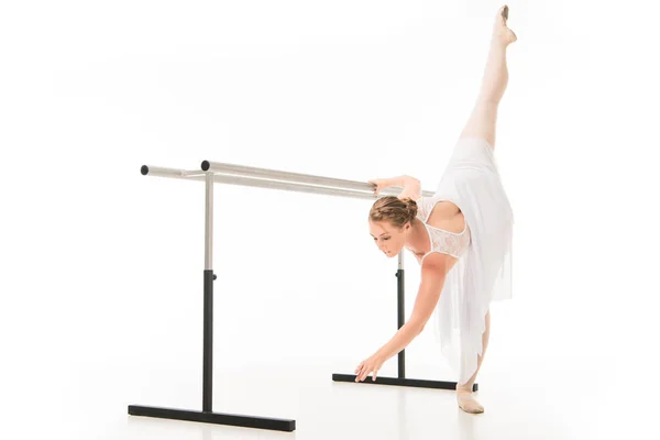 Bailarina en tutú y zapatos puntiagudos practicando en el stand de la barra de ballet aislado sobre fondo blanco — Stock Photo