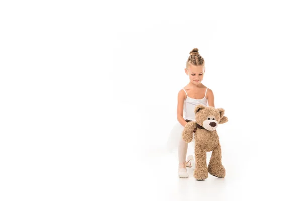 Heureuse petite ballerine en tutu assise avec ours en peluche isolé sur fond blanc — Photo de stock