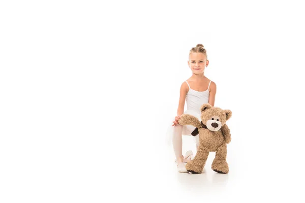 Adorable petite ballerine en tutu assise avec ours en peluche isolé sur fond blanc — Photo de stock