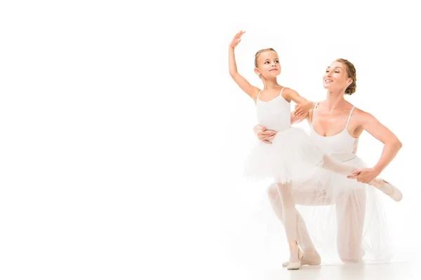 Smiling adult female coach helping little ballerina exercising isolated on white background — Stock Photo