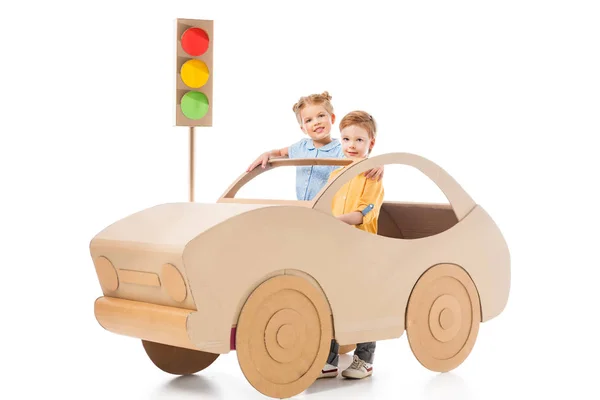 Adorable kids playing with cardboard car and traffic lights, on white — Stock Photo