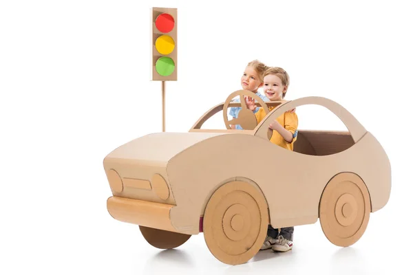 Brother and sister playing with cardboard car and traffic lights, on white — Stock Photo