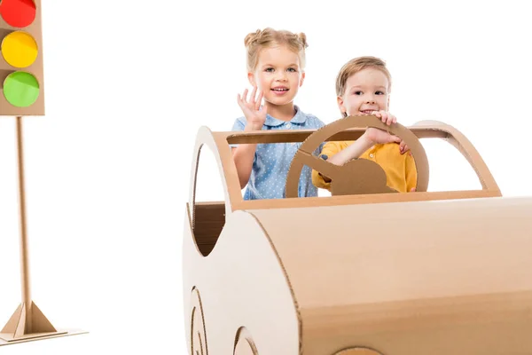 Crianças dirigindo carro de papelão com semáforos no fundo, isolado em branco — Fotografia de Stock