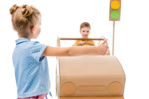 Adorable hermana autostop mientras hermano conducir coche de cartón, aislado en blanco — Stock Photo