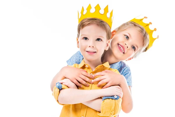 Schwester umarmt Bruder, Kinder in gelben Papierkronen, isoliert auf weiß — Stockfoto