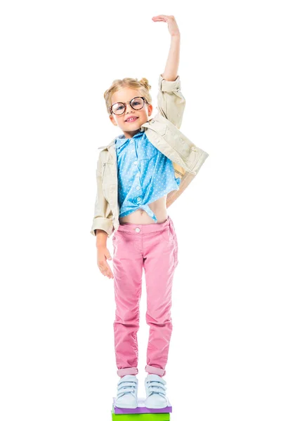 Glückliche Schülerin mit Brille, die auf Bücherstapel steht, um höher isoliert auf weiß zu sein, studiert Konzept — Stockfoto