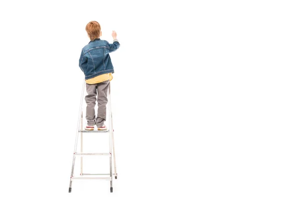 Back view of schoolboy standing on ladder and writing isolated on white — Stock Photo